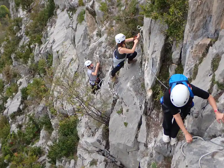 Via ferrata de Vicdessos – Ariège canyon aventure Alt : Participant en pleine ascension sur la via ferrata de l’arête sud à Vicdessos, Ariège