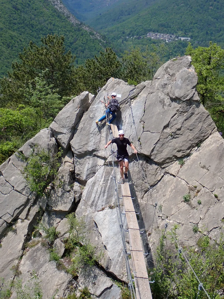 Participant à la via ferrata de l'arête sud de Vicdessos en Ariège traversant la passerelle suspendue
